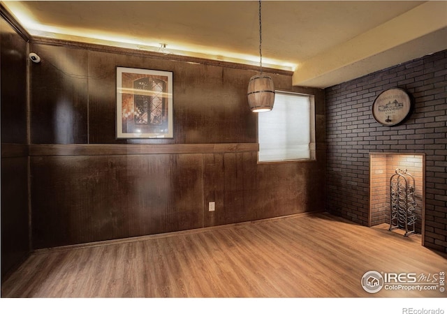 unfurnished dining area with wood finished floors, brick wall, and wood walls