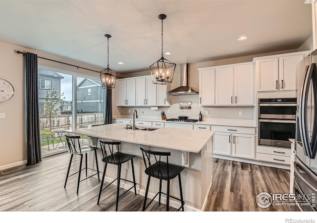 kitchen with a sink, wall chimney exhaust hood, light wood-style floors, light countertops, and recessed lighting