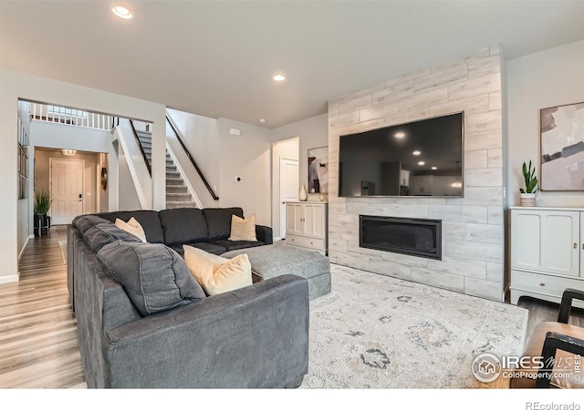 living area with wood finished floors, stairway, recessed lighting, a fireplace, and baseboards