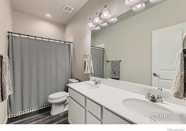 bathroom featuring wood finished floors, toilet, double vanity, and a shower with shower curtain