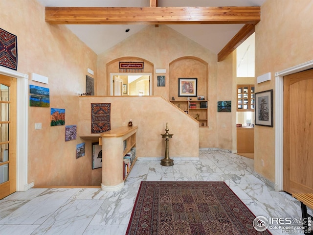 foyer with high vaulted ceiling, beam ceiling, marble finish flooring, and baseboards