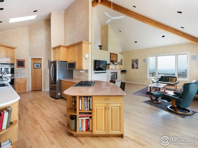 kitchen with appliances with stainless steel finishes, high vaulted ceiling, open floor plan, light brown cabinets, and light countertops