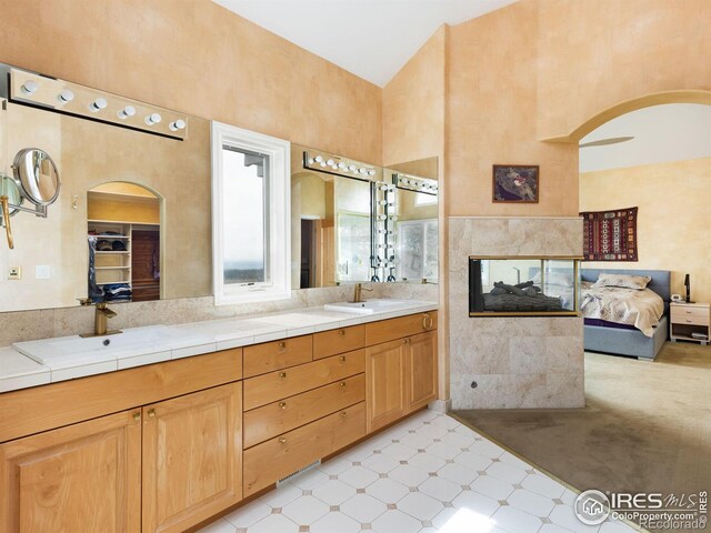full bathroom featuring a high ceiling, tile patterned floors, double vanity, and ensuite bathroom