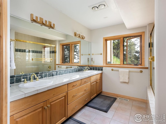 full bathroom with tiled shower, double vanity, tile patterned floors, and baseboards
