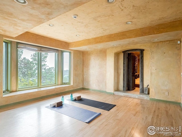 workout area with arched walkways, wood finished floors, recessed lighting, and baseboards