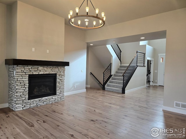 unfurnished living room featuring wood finished floors, baseboards, stairs, a high ceiling, and a chandelier