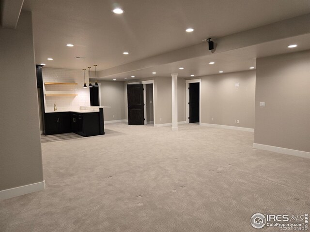 finished below grade area featuring recessed lighting, wet bar, light colored carpet, and baseboards