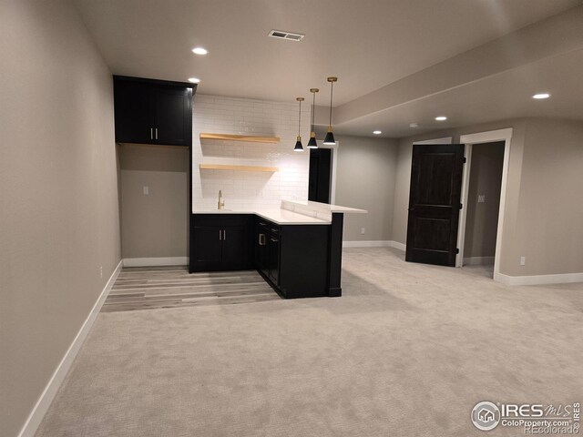 kitchen featuring dark cabinetry, a sink, light countertops, recessed lighting, and a peninsula