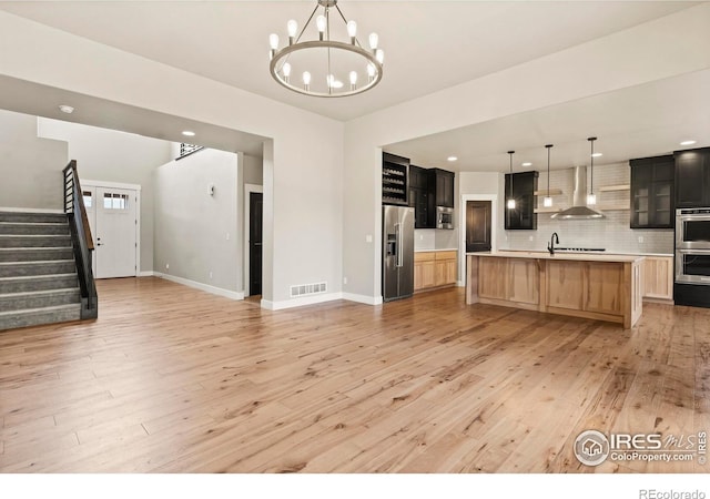 1940 Rolling Wind Dr, Windsor, CO 80550 - kitchen featuring appliances with stainless steel finishes, wall chimney exhaust hood, open floor plan, light countertops, and light wood finished floors