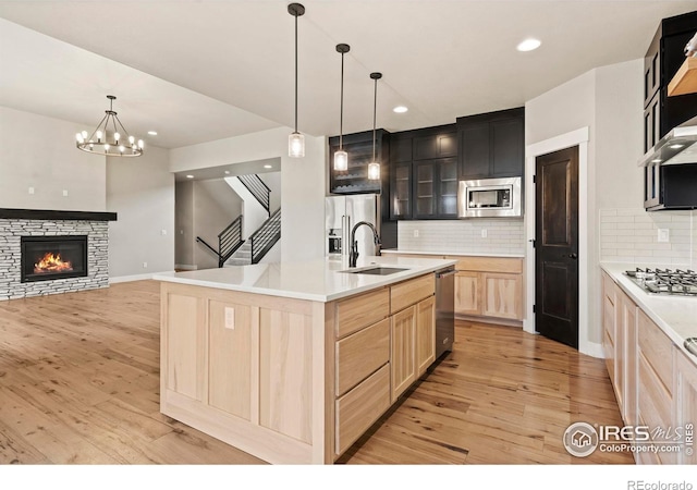 1940 Rolling Wind Dr, Windsor, CO 80550 - kitchen featuring light brown cabinetry, appliances with stainless steel finishes, a sink, light wood-style floors, and a chandelier