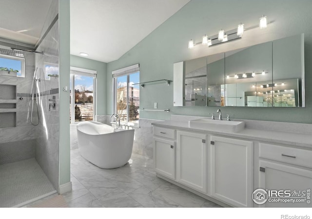 bathroom with walk in shower, marble finish floors, vaulted ceiling, vanity, and a freestanding tub