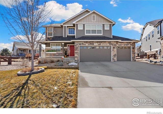 craftsman house featuring board and batten siding, driveway, a porch, stone siding, and an attached garage