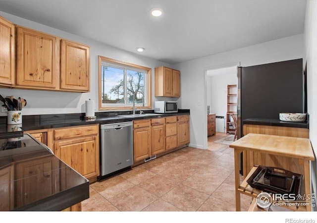 kitchen featuring stainless steel appliances, dark countertops, recessed lighting, a sink, and light tile patterned flooring