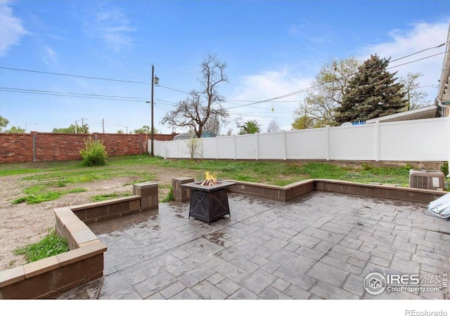 view of patio with a fire pit, a fenced backyard, and central air condition unit