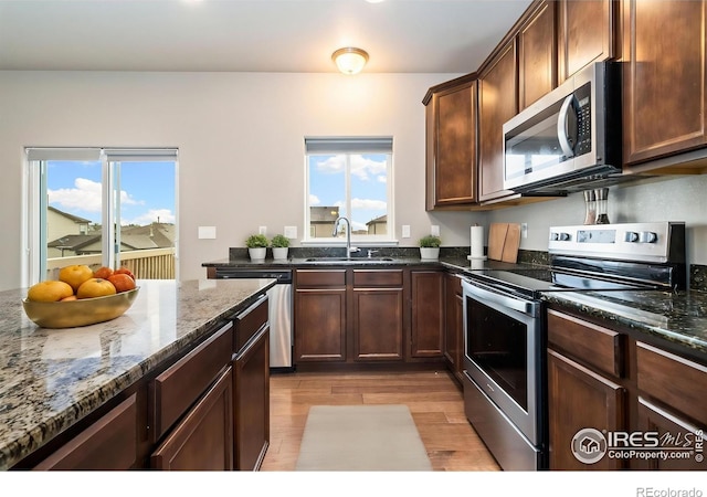 kitchen with stainless steel appliances, a sink, light wood-style flooring, and plenty of natural light