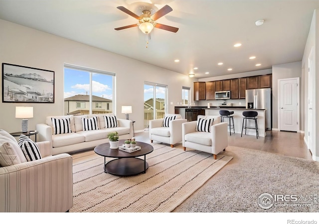 living area with a ceiling fan, recessed lighting, wood finished floors, and baseboards