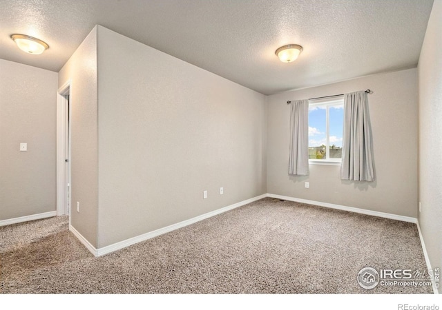unfurnished room featuring a textured ceiling, carpet, and baseboards