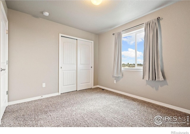 unfurnished bedroom with carpet, a closet, and baseboards