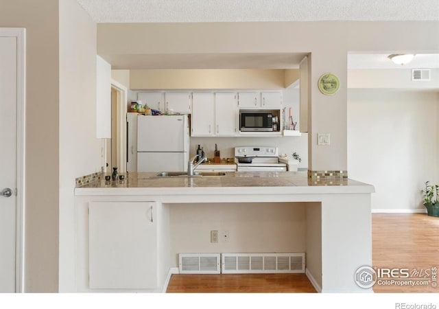4160 Monroe Dr Unit B, Boulder, CO 80303 - kitchen with white appliances, a sink, a peninsula, wood finished floors, and white cabinets
