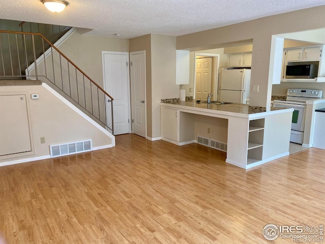4160 Monroe Dr Unit B, Boulder, CO 80303 - kitchen with white appliances, light wood-style floors, a peninsula, a textured ceiling, and white cabinets