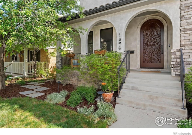 view of exterior entry with stucco siding and a porch