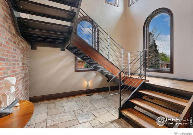 stairway with baseboards and stone tile flooring