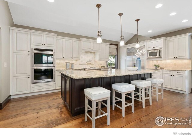 kitchen featuring built in appliances, lofted ceiling, backsplash, white cabinetry, and recessed lighting
