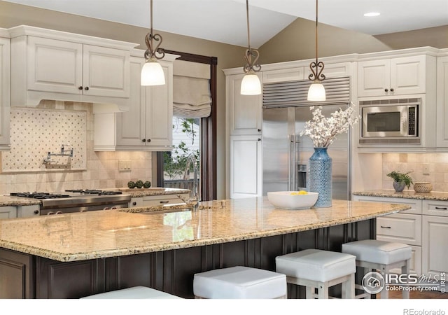kitchen with built in appliances, decorative backsplash, white cabinetry, a kitchen bar, and lofted ceiling