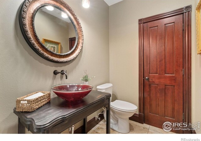half bath featuring tile patterned flooring, toilet, and vanity