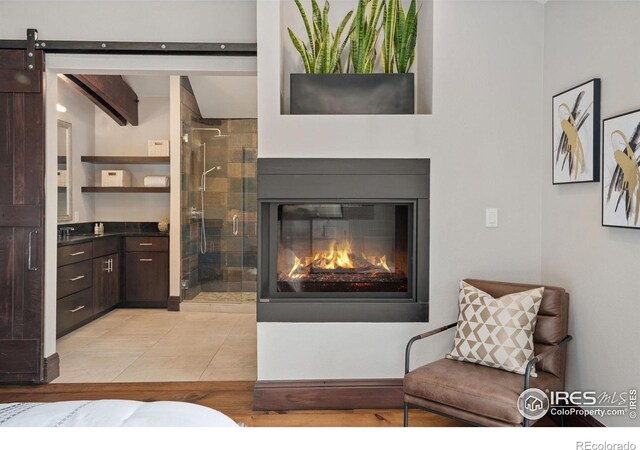living room with a glass covered fireplace, a barn door, and light tile patterned flooring