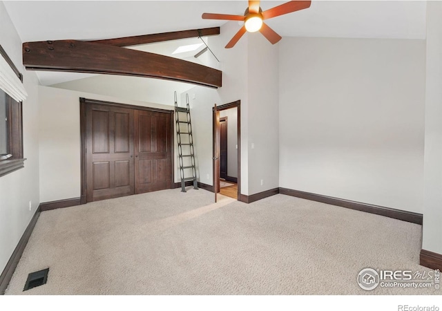 unfurnished bedroom with carpet, baseboards, beam ceiling, a closet, and high vaulted ceiling