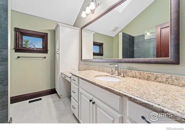 full bathroom with vaulted ceiling, vanity, tile patterned floors, and a skylight