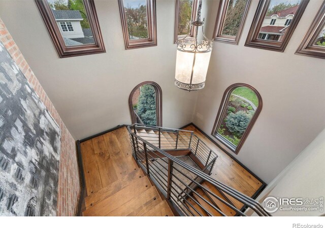 stairway with wood finished floors, a towering ceiling, and a chandelier