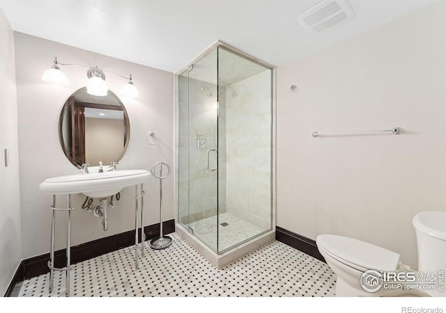 bathroom with toilet, baseboards, and a stall shower