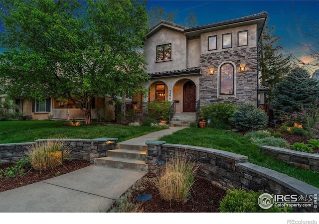 view of front of home featuring stucco siding, stone siding, a tiled roof, and a front lawn