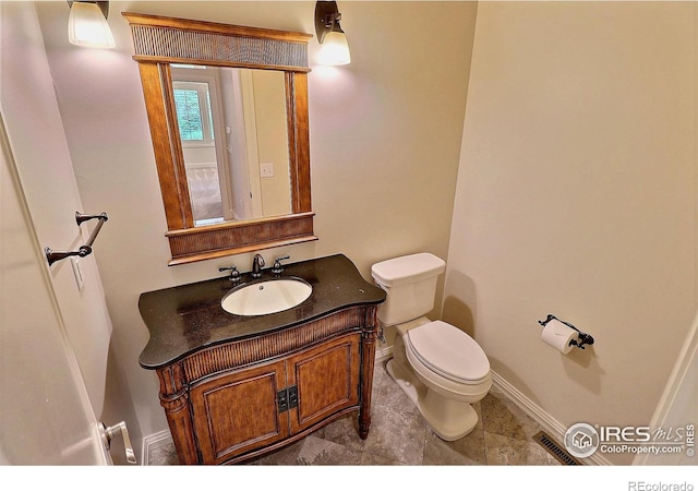 half bathroom featuring toilet, baseboards, and vanity