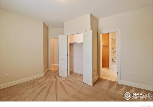 unfurnished bedroom with light carpet, connected bathroom, and baseboards