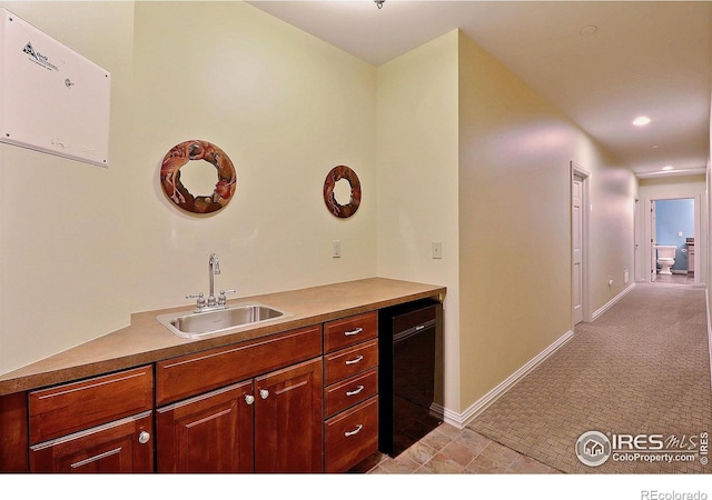 kitchen featuring a sink, baseboards, recessed lighting, light countertops, and light carpet