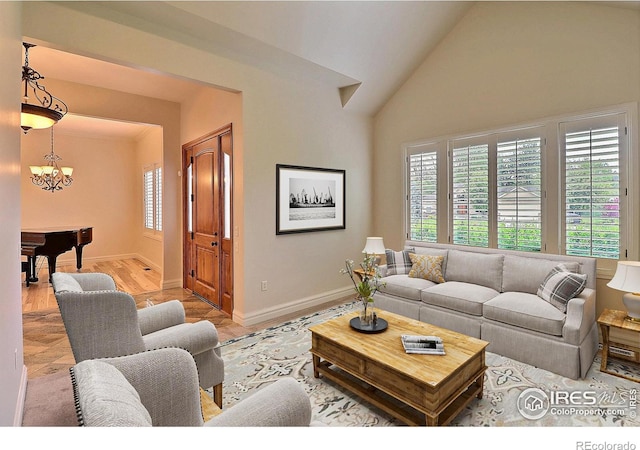 living area featuring baseboards, wood finished floors, high vaulted ceiling, and a chandelier