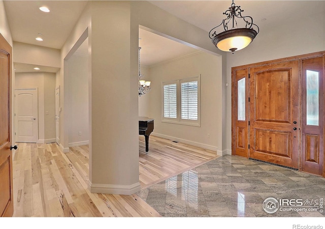 entryway featuring baseboards, a chandelier, recessed lighting, ornamental molding, and light wood-style flooring