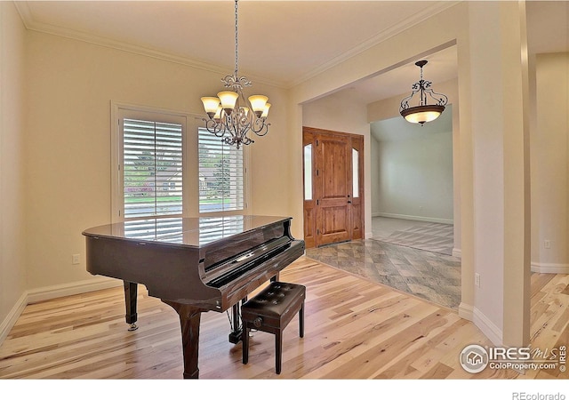 living area with wood finished floors, crown molding, a chandelier, and baseboards
