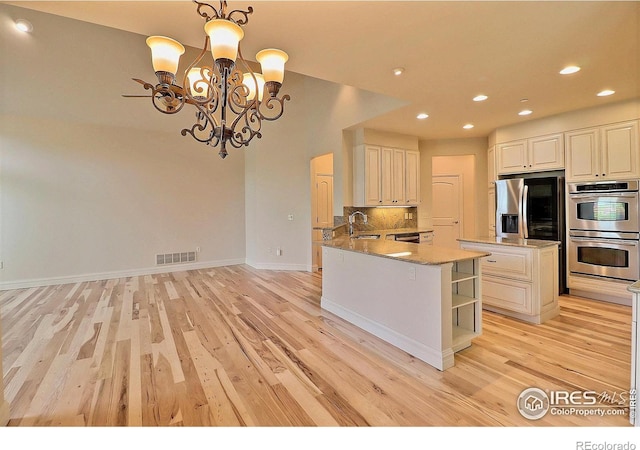 kitchen with stainless steel appliances, a chandelier, light wood-type flooring, open shelves, and decorative backsplash