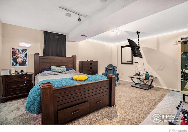 carpeted bedroom featuring track lighting and baseboards