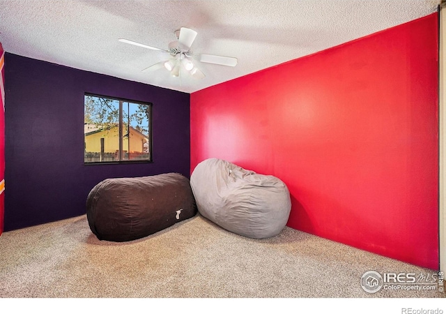 living area featuring carpet, a textured ceiling, and a ceiling fan