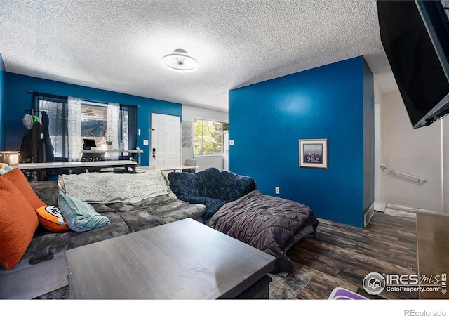 bedroom featuring wood finished floors, baseboards, and a textured ceiling