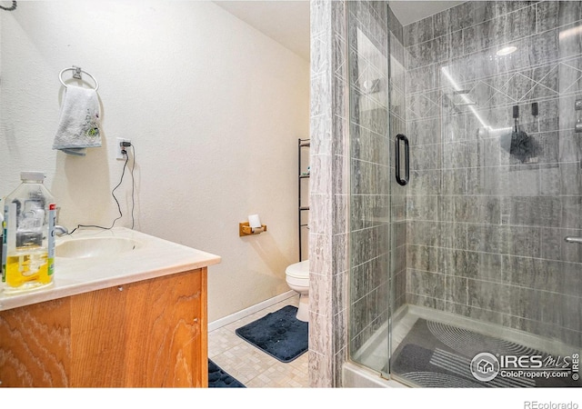 bathroom with a shower stall, vanity, toilet, and baseboards