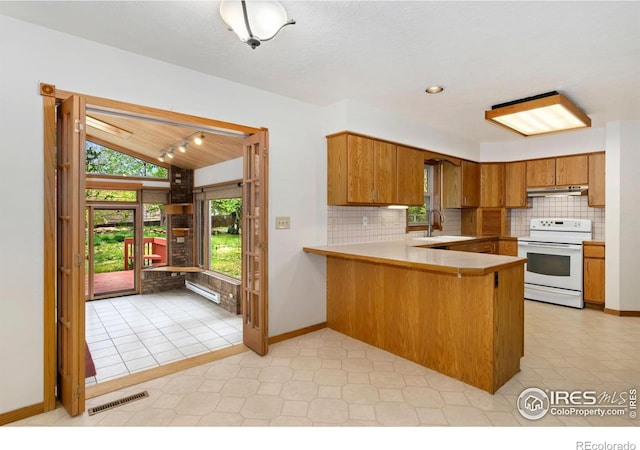 kitchen with electric range, lofted ceiling, brown cabinets, backsplash, and a peninsula