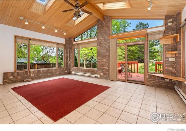 unfurnished sunroom featuring a skylight, baseboard heating, tile patterned floors, rail lighting, and wood ceiling