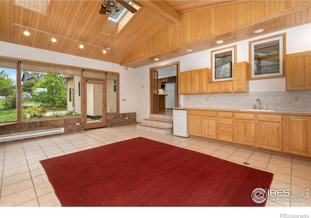 kitchen with light tile patterned flooring, a ceiling fan, a sink, a skylight, and refrigerator