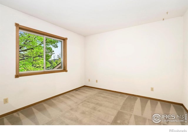 empty room with baseboards and light carpet